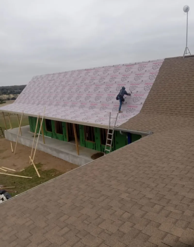 Worker preparing underlayment for a metal roof installation in Verona